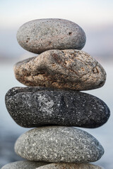 Balance pebble stone in the stoned beach at sunset. Stack of zen stones in harmony and balance with sea view. minimalist view of  stacked arrangement of pebbles on serene beach. mountain on background