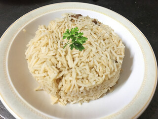 Cooked white rice in a plate with coriander side view closeup photo, 
