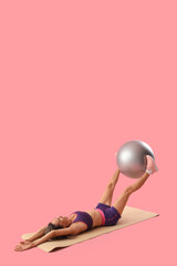 Beautiful adult woman exercising with fitness ball against pink background