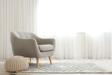 Minimal interior with armchair, carpet and pouf