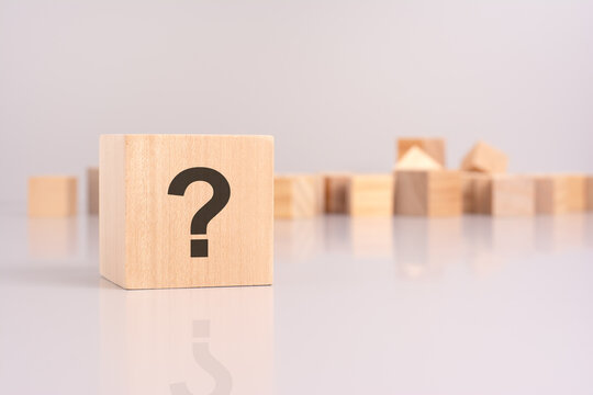 wooden cube with question mark over a grey background with copy space