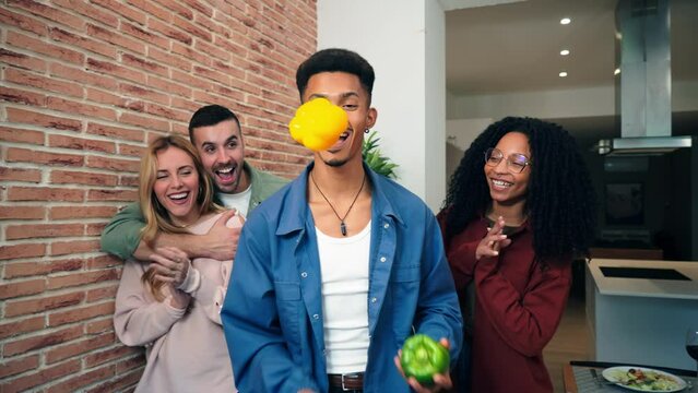 African american man havinf fun with his friends juggling with peppers at home. Slow motion of a funny guy playing with vegetables showing acrobat skills. Male performing throwing and catching food