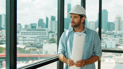 Professional architect engineer or male worker in casual outfit looking at skyscraper and city view...