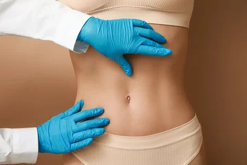 Fototapeten Young woman with flat belly and plastic surgeon on beige background, closeup © Pixel-Shot