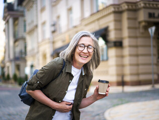 A woman wearing glasses holds a cup of coffee in her hand.