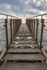 Long high and narrow steel stairs over high building with cloudy sky over it