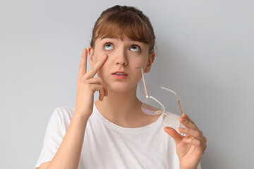Young woman with eyeglasses on light background. Glaucoma awareness month