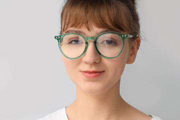 Young woman in eyeglasses on light background, closeup. Glaucoma awareness month