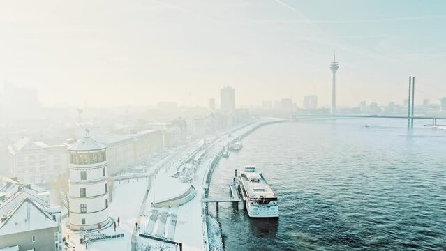 Icy Rhine with warm rays of sunshine over snow-covered rooftops in city of Düsseldorf