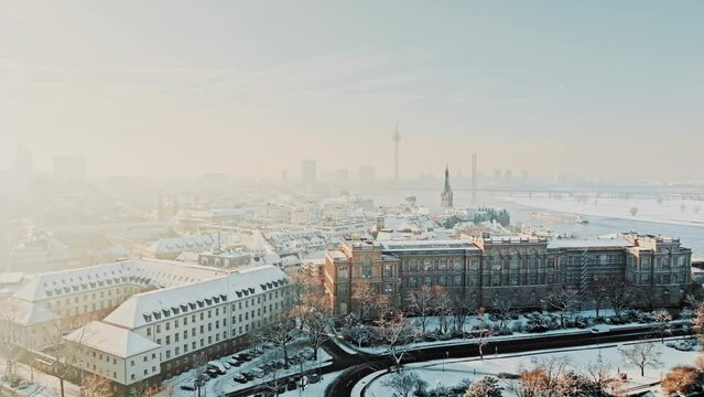Drone approaches snowy and cosy city of Düsseldorf in early winter morning 