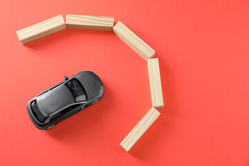 Development through barriers overcoming. Silver toy car movement blocked by wooden blocks on coral background, flat lay with space for text