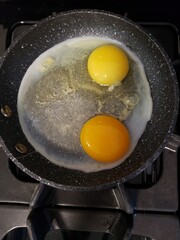 one duck egg and one chicken egg being fried in a fry pan
