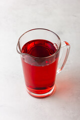 Red color drink in the glass jug on gray background.