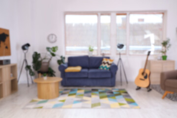 Blurred view of stylish living room with sofa, table and guitar