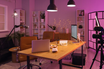 Podcaster's workplace with laptop and headphones in studio at night