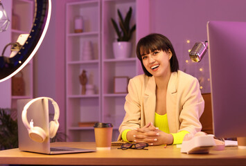 Young woman recording podcast in studio at night