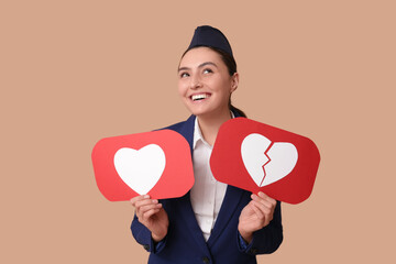 Beautiful young happy stewardess with heart like and dislike icons on beige background