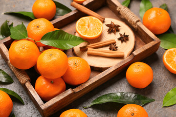 Wooden tray of sweet mandarins with cinnamon and star anise on dark background