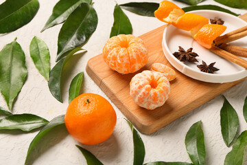 Wooden board of sweet mandarins with cinnamon and star anise on white background