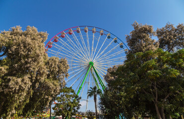 View of a Ferris wheel with colorful gondolas in Ayia Napa fun park. Cyprus, Mediterranean sea.