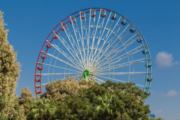 View of a Ferris wheel with colorful gondolas in Ayia Napa fun park. Cyprus, Mediterranean sea.