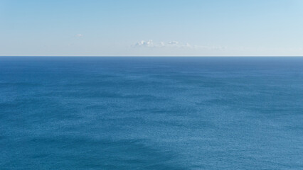 View at the horizon over blue ocean waves under a clear blue sky
