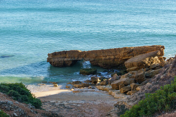 Beach and rock formation in front of the atlantic sea in golden sunlight at Santa Beach, Algarve,...