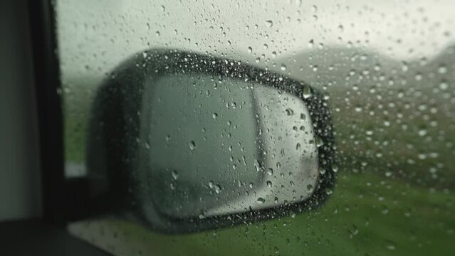 Raindrops Reflected On The Glass Of A Vehicle And The Rearview Mirror In The Background.