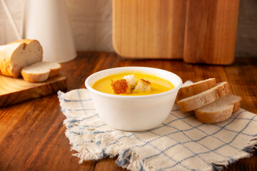 Homemade carrot and pumpkin cream soup. Easy, nutritious and healthy recipe. Served in a white bowl with bread croutons. Perfect to accompany everyday food.