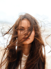 Wind-blown Beauty: A Young Attractive Caucasian Woman with Long Brunette Hair Posing Outdoors on a Sunny Beach