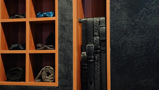 Assortment of man's bow tie and belts of shop's shelf at luxury business outfit store