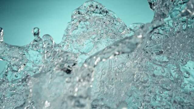 Super Slow Motion of Flying Water Splashes, Isolated on Blue Background. Filmed on High Speed Cinema Camera, 1000fps. Speed Ramp Effect.