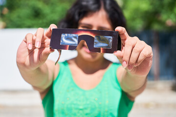 Happy young latina woman with solar eclipse glasses, watching a solar eclipse