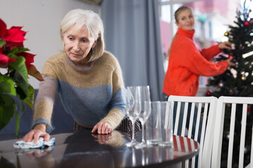 Mature woman cleaning table with rag at home before christmas
