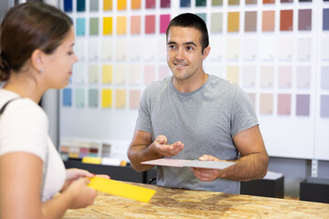 Seller of the hardware store advises the woman of the buyer what color to choose for ceramic tiles