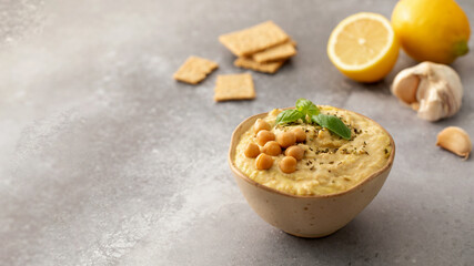 A dish of hummus made with chickpeas served with crackers on a table. Copy space