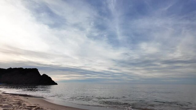 Beautiful dark turquoise sea with white, foamy waves hitting the beach sand. Beautiful bright sunset and sea.