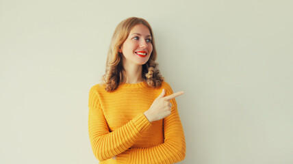 Portrait of happy smiling young woman pointing her finger to the side and looking away
