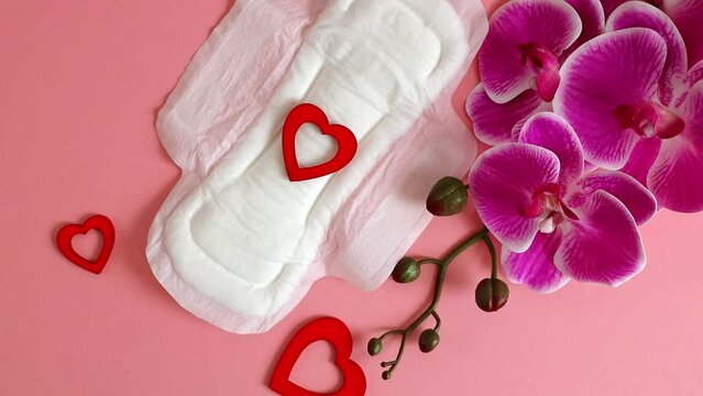 One feminine pad, three red hearts and an orchid branch on pink.
