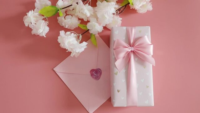 Gift box, envelope and apple tree branch on a pink background.