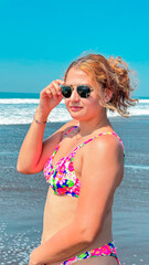Beautiful young woman in a pink bikini and sunglasses on the beach at sunny day. portrait