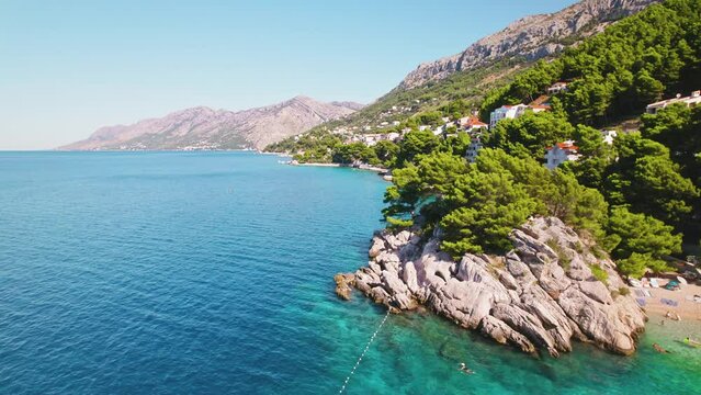 Breathtaking Coastline with Serene Sea. Stunning wide-angle view of a coastal region, tranquil blue ocean, greenery, and mountains in the background.