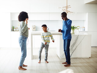 Fototapeta premium Cheerful afro american family - mom, dad and son dancing at home. Happy together.