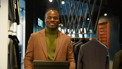 Confident african american man walking with shoe boxes in clothing store
