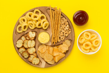 Board with unhealthy snacks on wooden background, top view