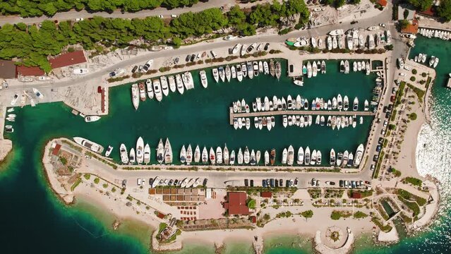 Boats and yachts moored on piers sit peacefully on water. Aerial view of structured nautical vessels in dock.