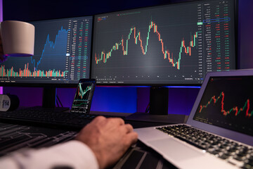Cropped trader businessman hands view analyzing in two dynamic stock exchange investment screen on...
