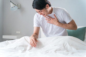 Obraz na płótnie Canvas ベッドの上で胸を苦しがる急病の男性（苦しい・発作・心筋梗塞・心臓発作・動悸・狭心症） 