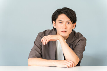 机に座る男性モデル（おしゃれ・ナルシスト）
