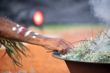 Human hand with green branch of eucalyptus, smoke and fire, the smoke ritual rite at a indigenous...